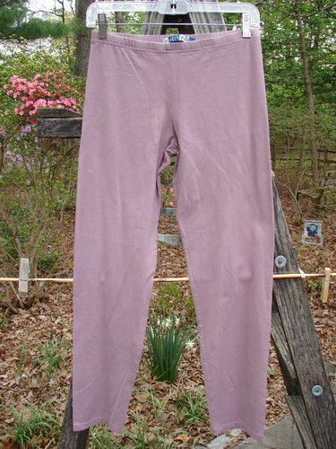 Barclay Cotton Lycra Crop Lightweight Legging Unpainted Lilac Size 0 draped over a wooden fence, showcasing its full thinner elastic waistband and tapering lowers, highlighting its vintage-inspired design.