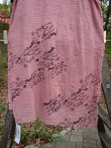 Barclay NWT Crinkle Cotton Scarf Wheat Field Plum Rose OSFA displayed on a wooden stand, showcasing intricate black designs on a pink organic cotton fabric, perfect as a shawl or waist wrap.