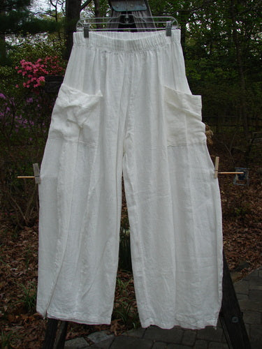 Barclay Linen Side Pocket Tie Pepper Pant Unpainted White Size 1 hanging on a clothesline, showcasing its billowy shape, elastic waistline, and exterior pockets, ideal for versatile spring styling.