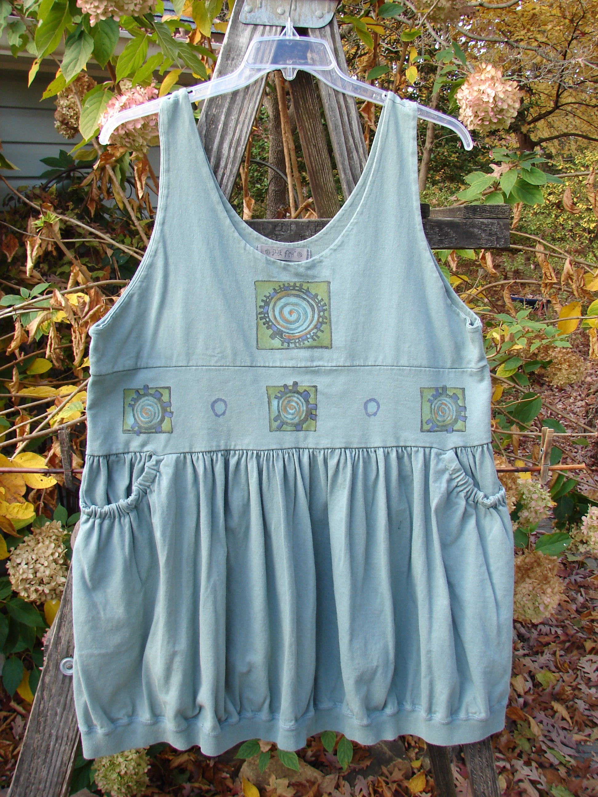 1996 Amusement Jumper Round Wind Trinket Size 1 displayed outdoors, features detailed wind-themed painting, double-layered bodice, and elastic pockets, embodying BlueFishFinder's unique vintage clothing style.