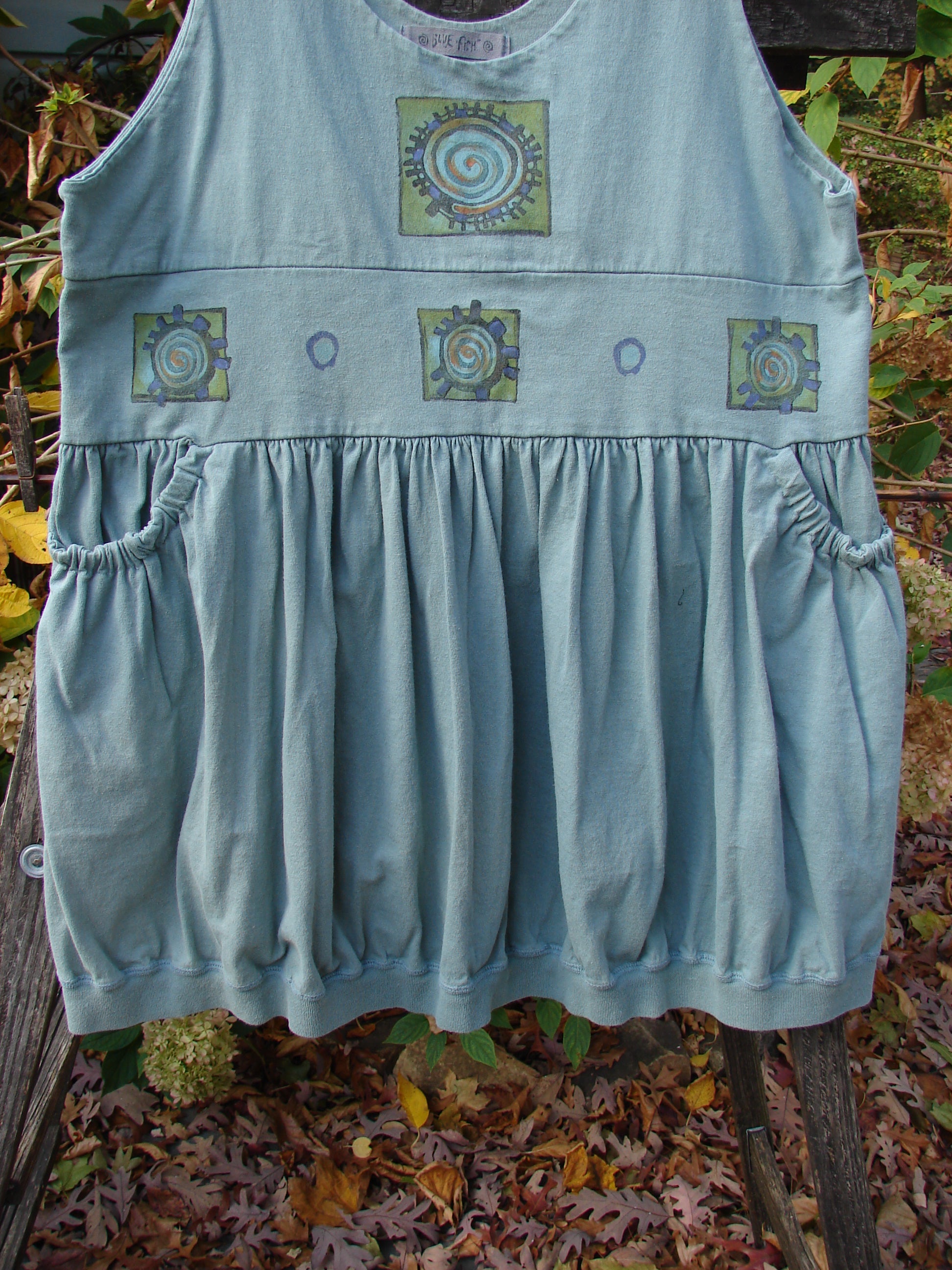 1996 Amusement Jumper Round Wind Trinket Size 1 featuring a unique wind-themed pattern, draw cord back, and elastic front pockets, showcasing the vintage Blue Fish Clothing's creative style.