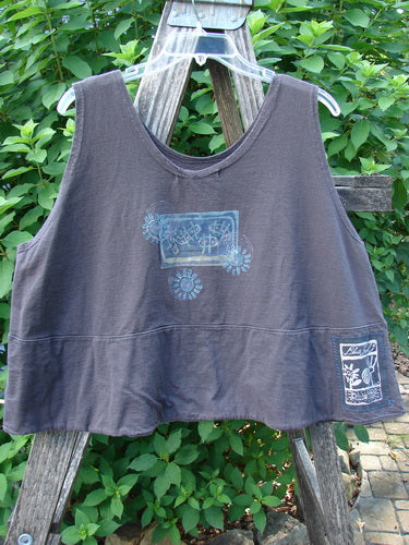 1995 Klee Top Garden Friends Shadow Size 1, a sleeveless, cropped tank with a loose, boxy cut, features light-colored graphics, a scooped neckline, and a distinctive hemline, draped over a wooden ladder.