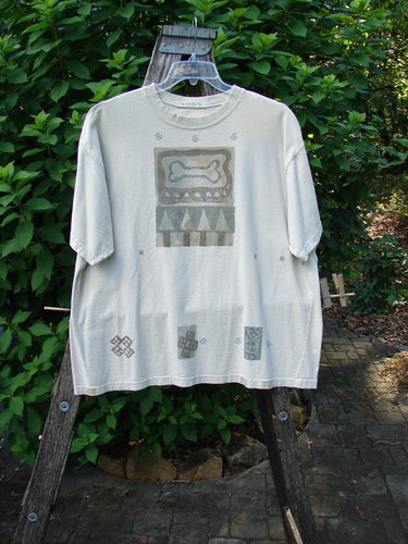 1995 Short Sleeved Crop Tee Doggie Bone Beach Glass Size 1, featuring a doggie bone theme and Blue Fish patch, displayed on a wooden rack, highlighting its drop shoulders and thicker ribbed neckline.