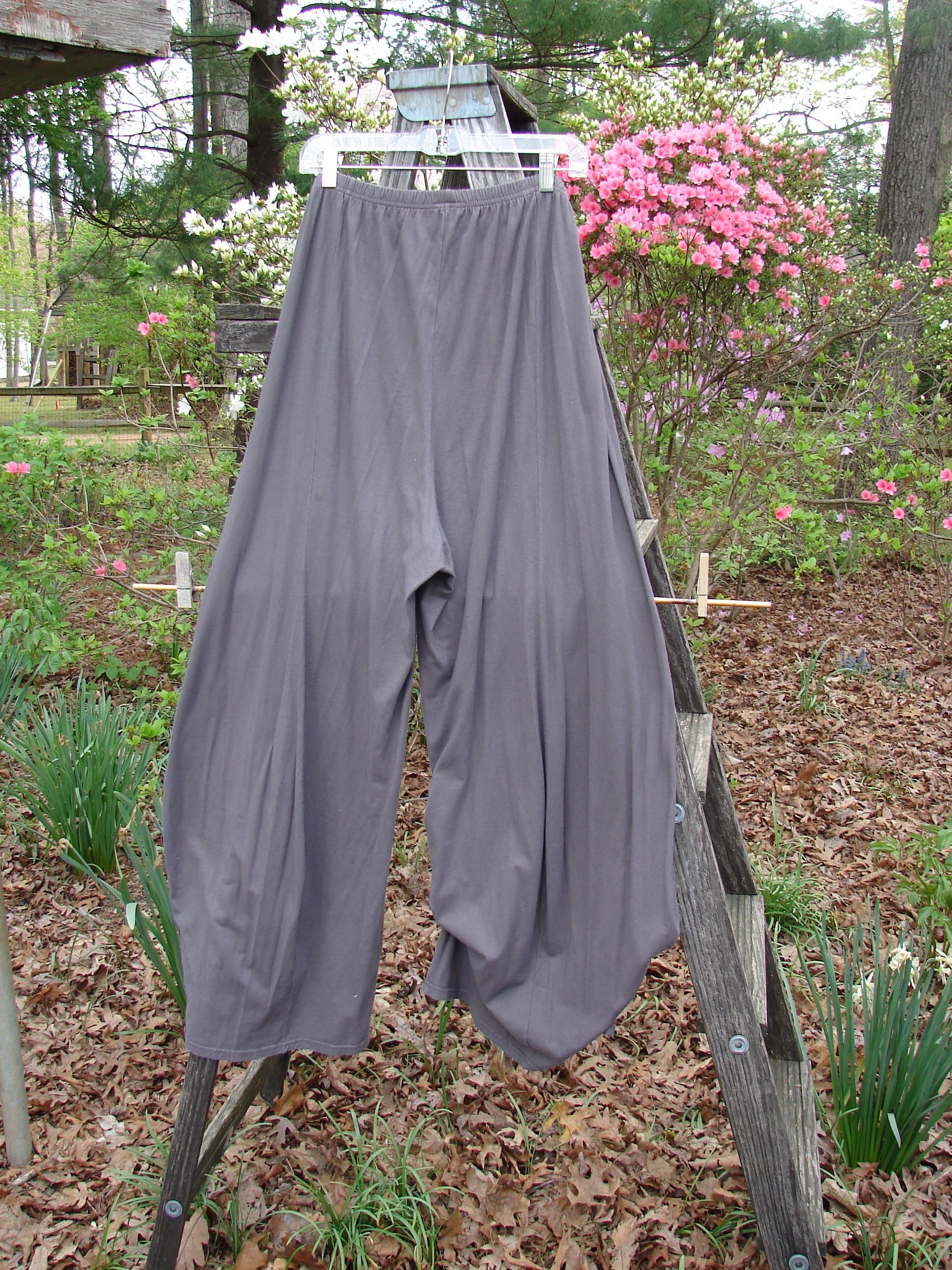 Barclay Lightweight Tie Bottom 4 Square Pant Unpainted Grey Granite Size 0 displayed on a garden ladder, showcasing the full elastic waistline and billowing lower fall design amidst lush greenery.