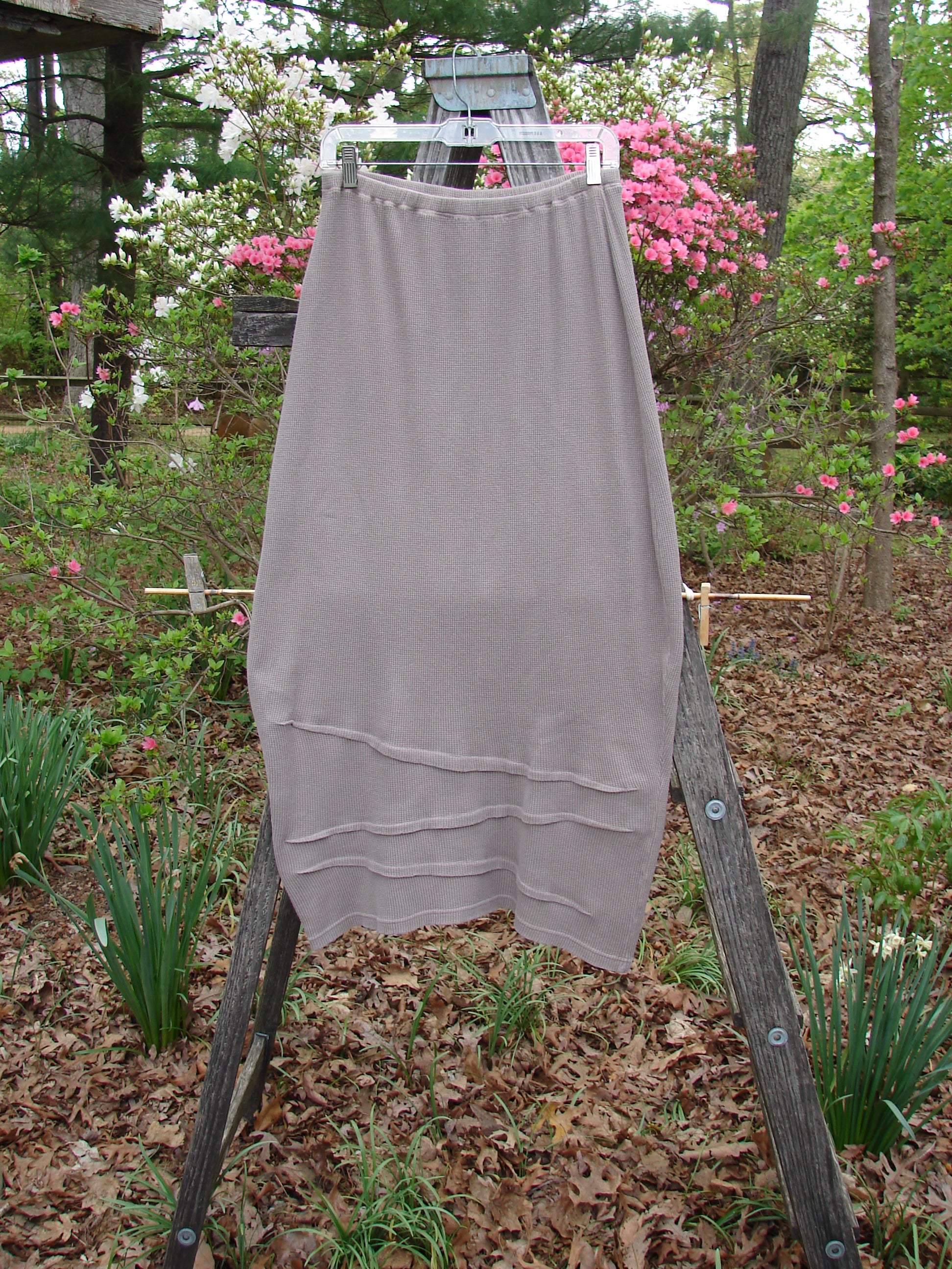 Barclay Thermal Awen Skirt Unpainted Stone Size 0 displayed on a wooden ladder, showcasing its unique bell shape and textured diagonal hemline, reflecting Bluefishfinder.com's vintage fashion ethos.