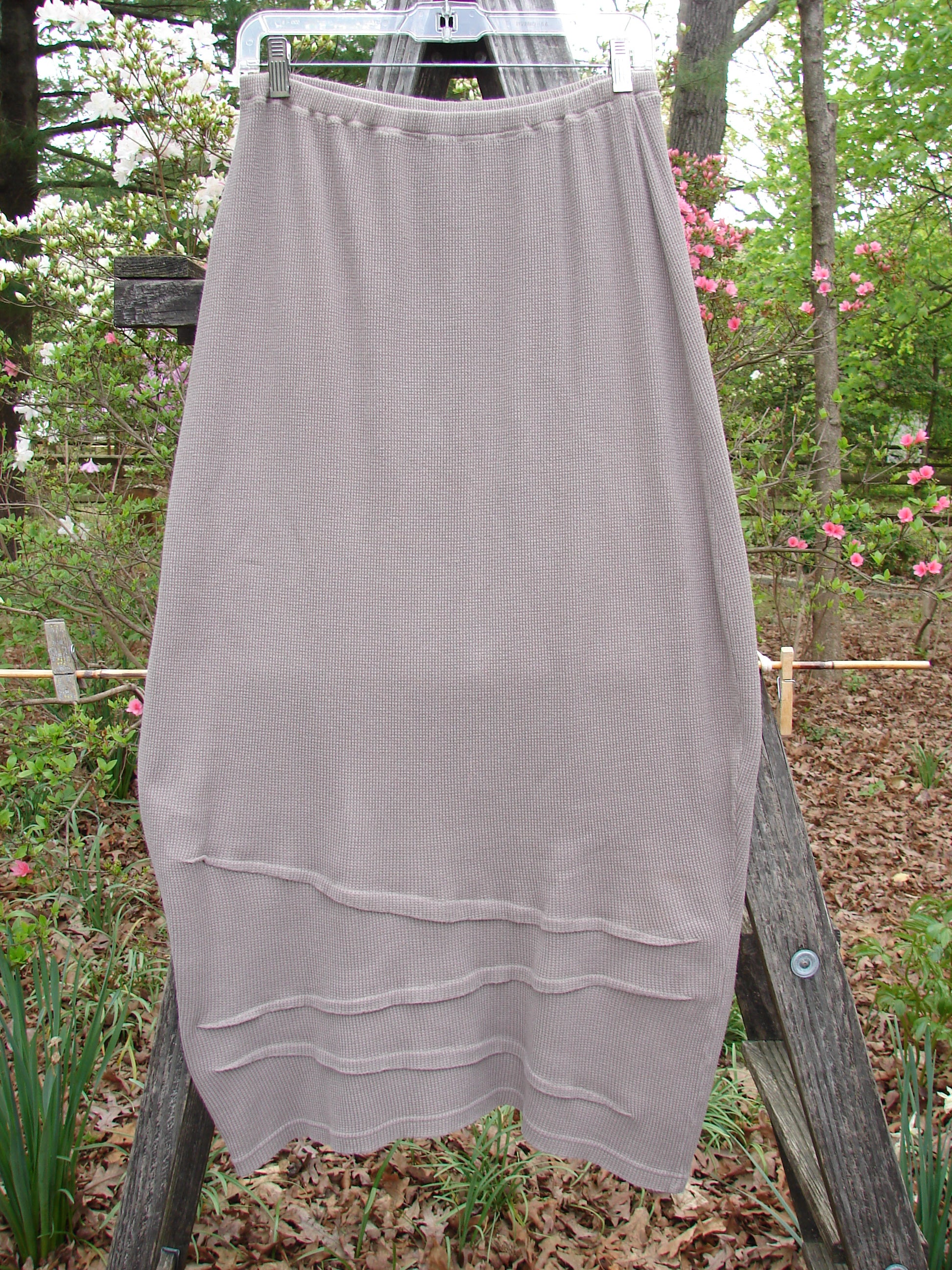 Barclay Thermal Awen Skirt Unpainted Stone Size 0 displayed on a wooden ladder, showcasing its unique bell shape, textured hemline, and full elastic waistband, emphasizing its vintage-inspired design.