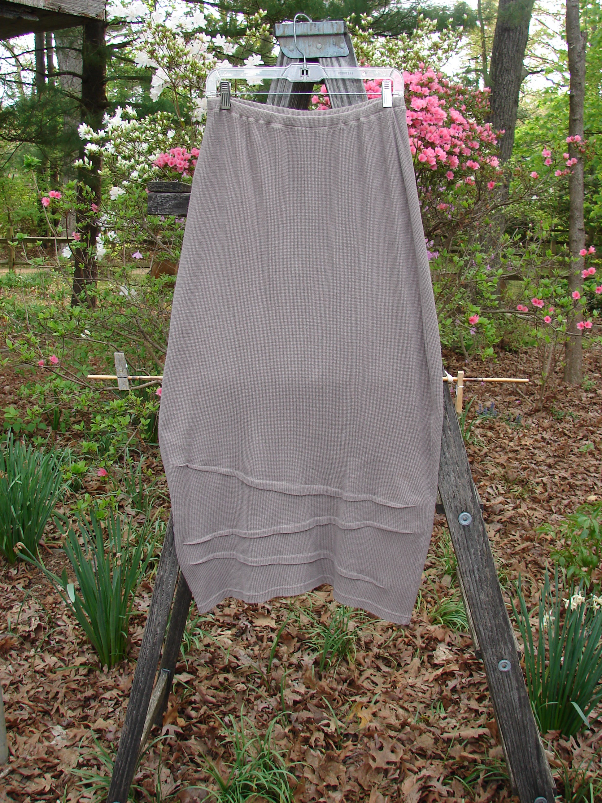Barclay Thermal Awen Skirt Unpainted Stone Size 0 displayed on a wooden ladder, showcasing its unique bell shape and textured hem.