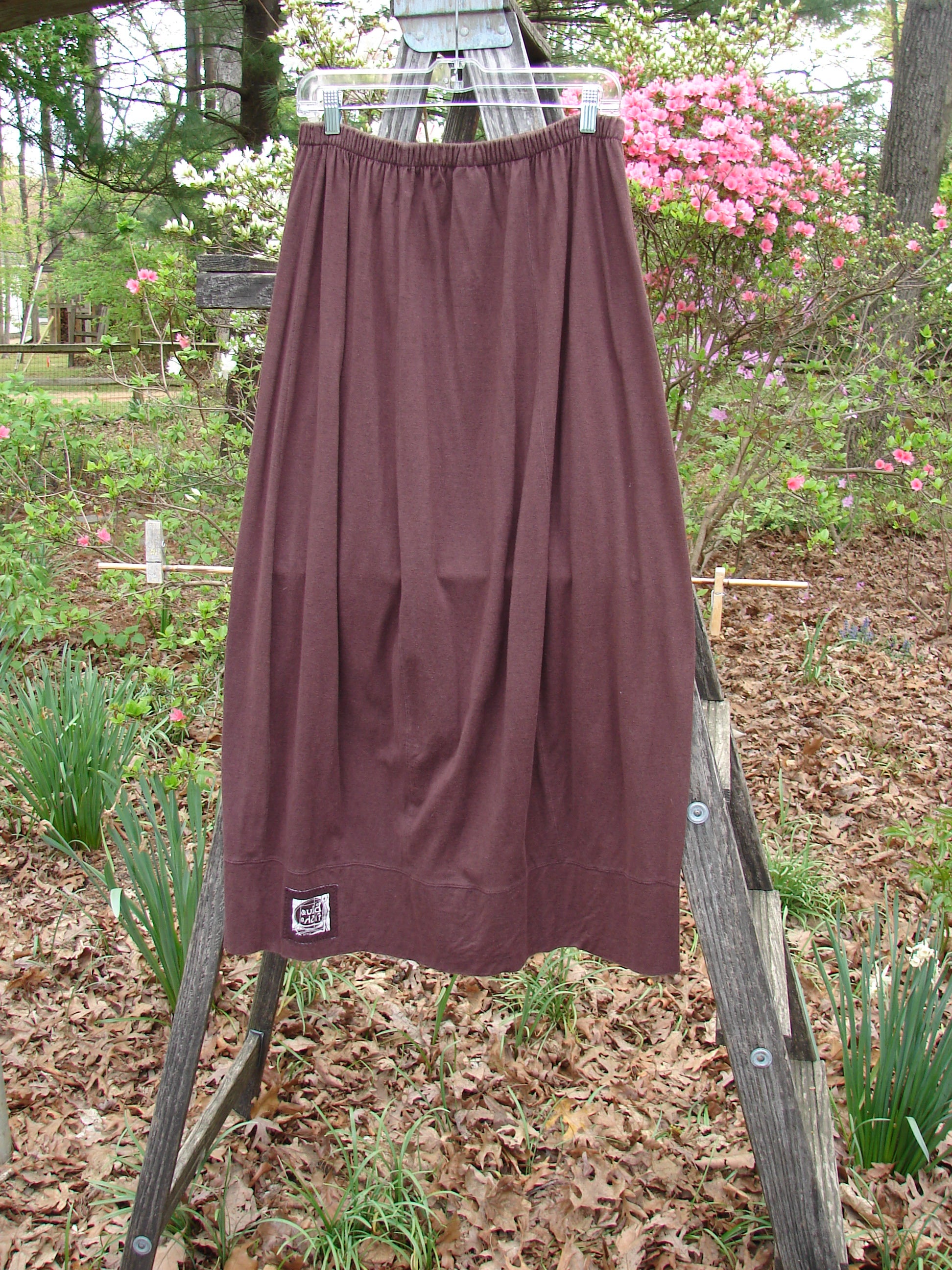 1998 Wool Merino Pria Skirt Unpainted Raisin Size 1 displayed on a wooden stand, showcasing a unique four-square lower shape with sectional panels and horizontal seams, capturing vintage Blue Fish Clothing style.