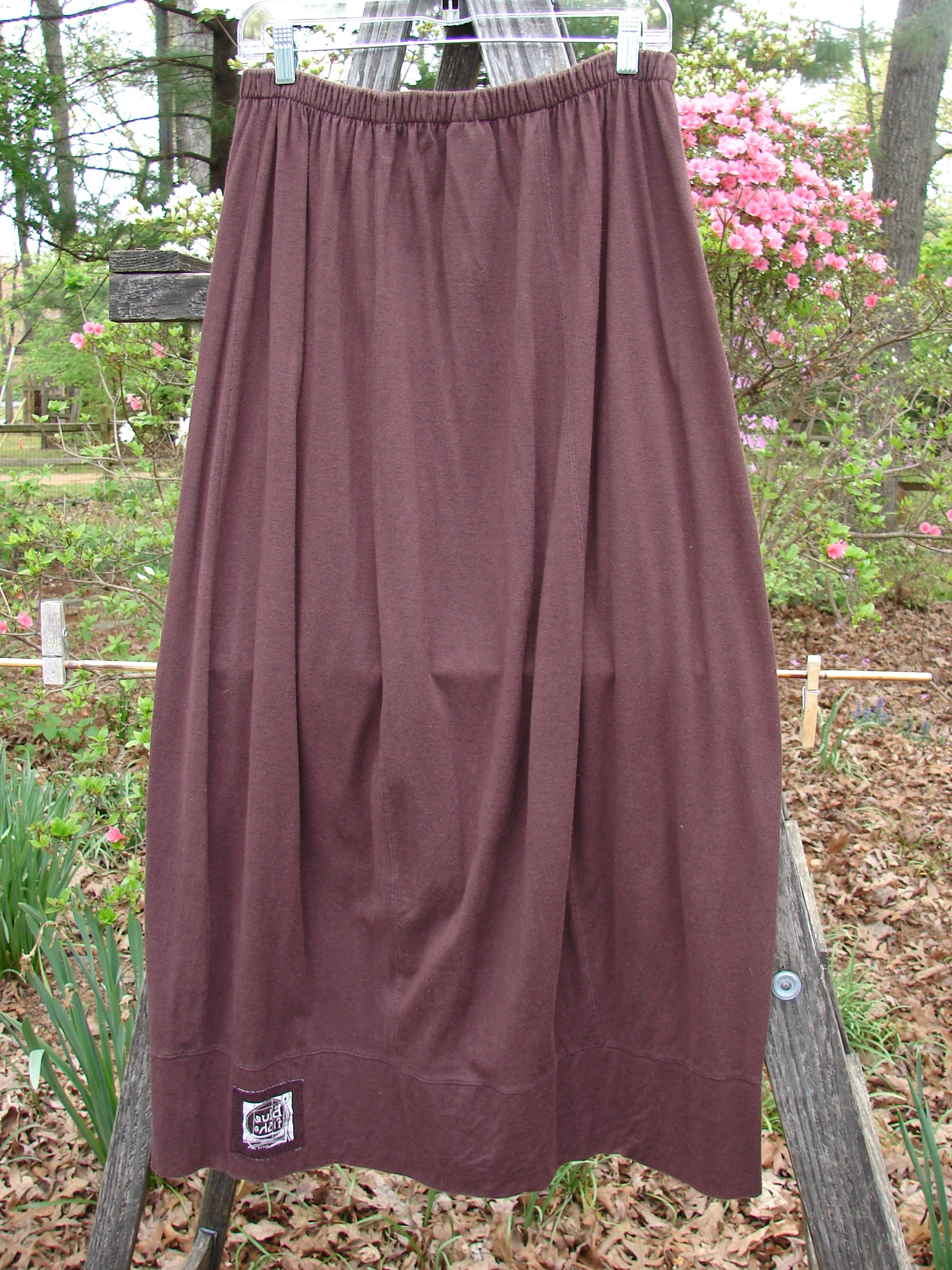 1998 Wool Merino Pria Skirt Unpainted Raisin Size 1 displayed on a wooden fence, showcasing its unique diagonal seams and sectional panels, part of BlueFishFinder.com's vintage collection.