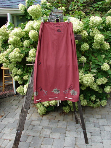 1992 Buttonloop Skirt Pomegranate Music OSFA displayed draped on a wooden ladder, showcasing its drawcord waist, bell shape, and buttonhole details with hand-dyed silk ribbons.