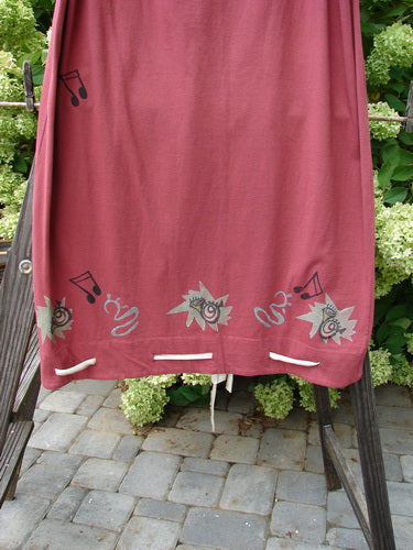 1992 Buttonloop Skirt Pomegranate Music OSFA displayed on a rack, showcasing its drawstring waist, button holes, and unique hemline. Visible intricate designs highlight its vintage appeal.