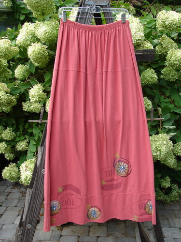 1998 Scrabble Skirt Games Cerise Size 2: A long pink skirt with a tree and flower illustration, featuring a waistline with flat folded front, rear elastic, and horizontal panels.