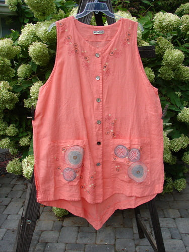 Barclay Linen Katy Vest Circle Spin Tangerine Size 2, featuring thick pearly buttons, varying hemline, oval neckline, two exterior pockets, deeper arm openings, and unique rear upper waist seam, hanging on a rack.