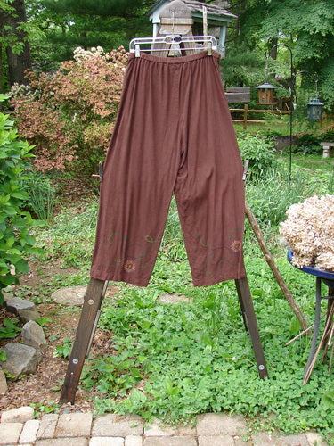 Barclay Tencel Collar Drawstring Studio Duo Spin Flower Sepia Size 1: A pair of pants on a clothesline with a close-up of a dog and a metal pole with a metal bar in the middle of a green field.