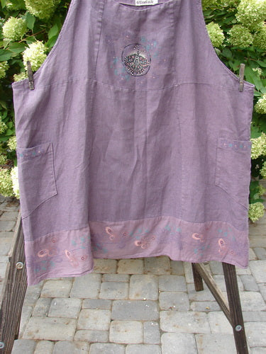 Barclay Linen Patterson Flutter Apron Jumper, Size 2, in Dusty Plum. Medium weight linen with cotton batiste accents. Features include mega sectional panels, lower full hem circumference batiste flutter, two drop wrap exterior side pockets, and garden beautiful butterfly theme paint. Adjustable shoulder straps. Bust 22 and open, waist 60, hips 64, sweep 75. Length is 40 to 50 inches, shoulder strap dependent.