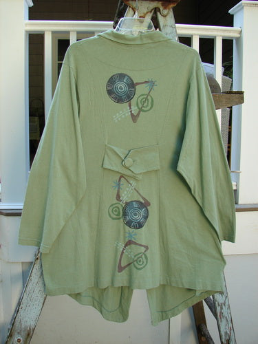 1996 Boulevard Jacket Giant Pinwheel Spanish Moss Size 0: A green jacket with a design on it, featuring a button-accented and cut collar, button-tabbed back, varying shirttail hemline, and two side pockets. Perfect for Blue Fish collectors!