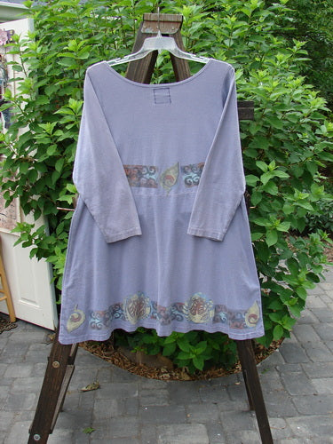 1993 Sparrow Dress Continuous Celtic Periwinkle OSFA hanging on a rack, featuring a downward yoked waist seam, two wooden button upper closure, and a varying hemline.