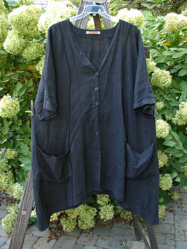 Barclay Linen Double Tie Back Jacket in unpainted black on a rack, showcasing a deep V neckline, A-line sweep, vertical stitchery, drop pockets, and varying hemline, perfect for mixing and matching.