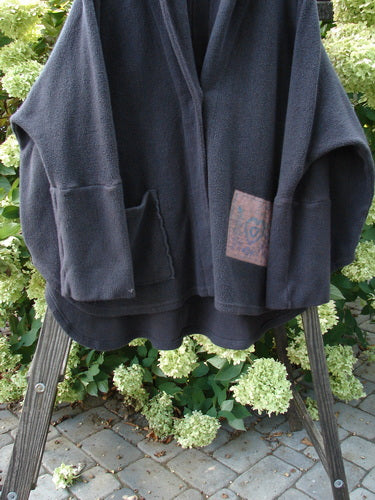 Barclay Patched Celtic Moss Deco Coat Farmhouse Brum OSFA on a rack, featuring oversized vintage buttons, deep V neckline, foldable lower sleeves, and a front oversized pocket.