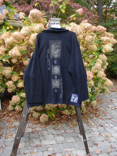 1995 Reprocessed Deco Jacket Polka Gal Black OSFA on a wooden stand, showcasing its double-button closure, drop dolman shoulders, and diagonal oversized pockets, embodying vintage Blue Fish Clothing charm.