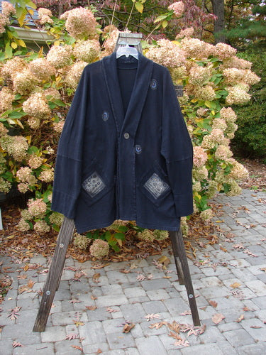 1995 Reprocessed Deco Jacket Polka Gal Black OSFA displayed on a rack, showcasing its drop dolman shoulders, double button hole, deep V neckline, and oversized painted pockets in a vintage style.