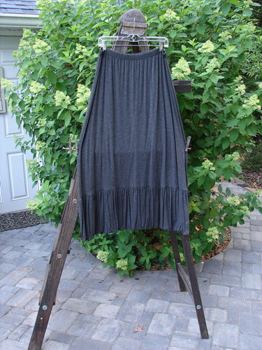 2000 Rayon Lycra Midi Bubble Trio Sparkle Border Charcoal Size 1 2: A skirt on a rack with ruffles, a grey dress, and a close-up of a plant.