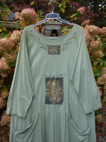 1995 Farmer Jen Dress Fall Leaves Dinette Green Size 2 displayed on a mannequin, showcasing cozy long sleeves, a wider neckline, and multiple functional pockets. The dress features a charming A-line shape.