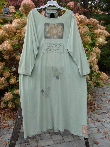 1995 Farmer Jen Dress Fall Leaves Dinette Green Size 2 displayed on a rack, showcasing a rounded neckline, longer sleeves, multiple pockets, and fall leaves theme paint in vintage Blue Fish Clothing style.
