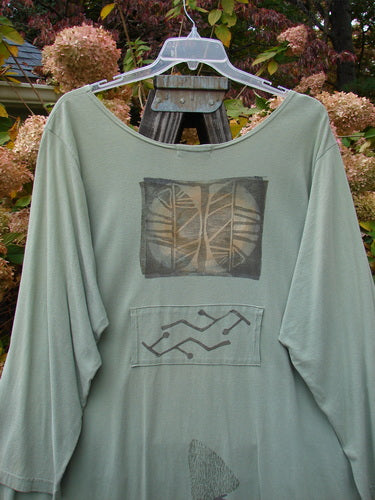 1995 Farmer Jen Dress Fall Leaves Dinette Green Size 2 displayed on a hanger, showcasing the long sleeves, rounded neckline, multiple pockets, and pleats, highlighted by a fall leaves theme design.