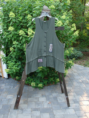 Barclay Thermal Patched Susset Vest High Back Chair Forest Size 2 displayed on a wooden rack, featuring two diagonal pockets, detachable bottom flounce, deep arm openings, and wooden buttons.