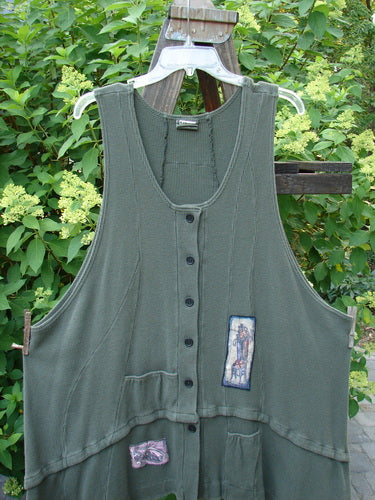 Barclay Thermal Patched Susset Vest on a high back chair, featuring front pockets, detachable flounce, deep arm openings, wooden buttons, and painted patches.