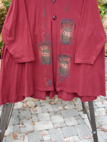 1997 Mask Jacket Primitive Vase Regalia Size 2 – A bell-shaped red jacket with a vase design, two button closure, deep side pockets, and a rounded hemline.