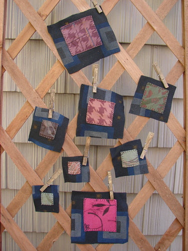 Image alt text: "A group of fabric squares featuring a winter mixed theme patch collection mounted on a wooden lattice"