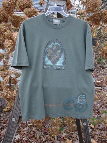 2000 Short Sleeved Tee Belonging Highland Size 1: A t-shirt on a swinger with a graphic on it, featuring a painting and wood plank details.