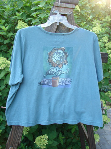 2000 Pocket Crop Tee Top Earth Day Blue Mineral Size 2 displayed on a hanger, featuring a swingy hemline, rolled neckline, double-layered front pocket, and Earth Day theme paint.
