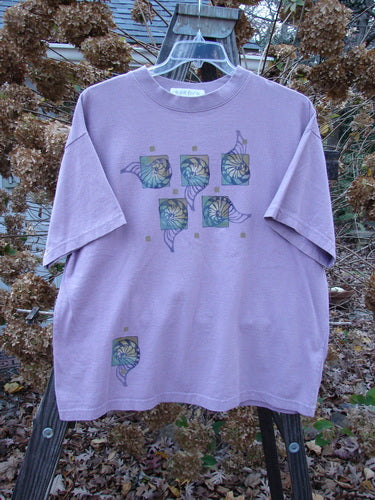 1997 Short Sleeved Tee Five Shell Jasmine Size 1: A purple t-shirt with a design on it, featuring a thicker ribbed neckline and a slightly shorter, boxier shape. Made from medium weight organic cotton jersey. Bust 50, waist 50, hips 50, length 27 inches.