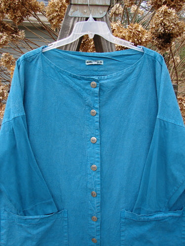 Barclay Cotton Sleeve Hemp Jacket Unpainted Aqua Size 2 displayed on a hanger, showcasing its rounded boatneck, full metal button front, oversized pockets, vertical panels, and slimmer sleeves with medium wear and fade.