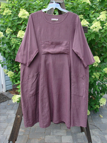 Barclay Linen Cotton Sleeve Upper Pocket Dress Unpainted Red Plum Size 2 displayed on a hanger, featuring a rounded neckline, sectional panels, and three-quarter length sleeves with a cotton lettuce edge.