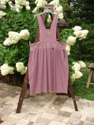 1996 Souvenir Jumper Abstract Path Petunia Size OSFA displayed on a wooden rack, featuring a gathered skirt, crisscross back, and painted bib, showcasing Bluefishfinder.com’s vintage, expressive style.