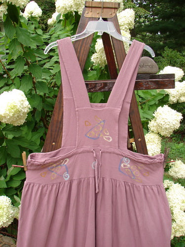 1996 Souvenir Jumper Abstract Path Petunia Size OSFA displayed on a swing, highlighting its full gathered skirt, criss-cross back, and painted bib, capturing the vintage charm of Blue Fish Clothing.