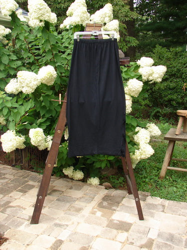 1993 Tie Skirt Unpainted Black Size 1 displayed on a rack, featuring a full elastic waistline, slight pegging, and short velvet side ties, from the Holiday Collection in mid-weight cotton jersey.