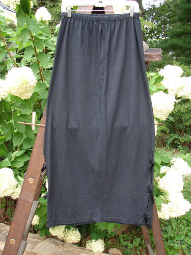1993 Tie Skirt Unpainted Black Size 1 displayed on a wooden stand, featuring a full elastic waistline, slightly pegged and vented design, with short velvet side ties.