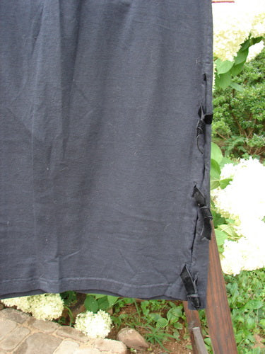 1993 Tie Skirt Unpainted Black Size 1 displayed on a wooden pole, showcasing its full elastic waistline, slightly pegged and vented design, and short velvet side ties.