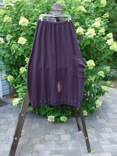 Barclay Patched Thermal Side Pocket Skirt in Red Plum, displayed on a wooden stand, featuring a wide shape, ribbed hemline, and an oversized side pocket.