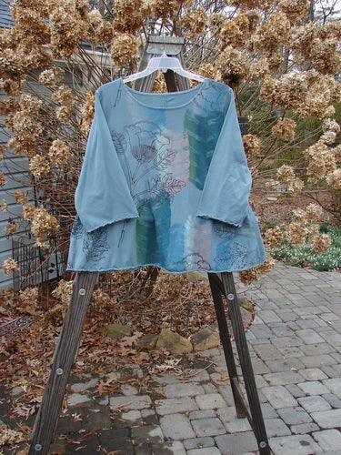 Image alt text: "Barclay Three Quarter Sleeved Crop A Lined Tee Top with Single Sprig design on blue shirt, displayed on a swinger with wooden legs"