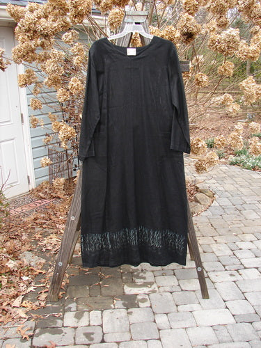 2000 Ringlet Dress Grass Row Black Size 1 displayed on a rack, showcasing its long sleeves, oversized pockets, and unique V-shaped neckline. The dress has a widening shape with a double drawcord back.