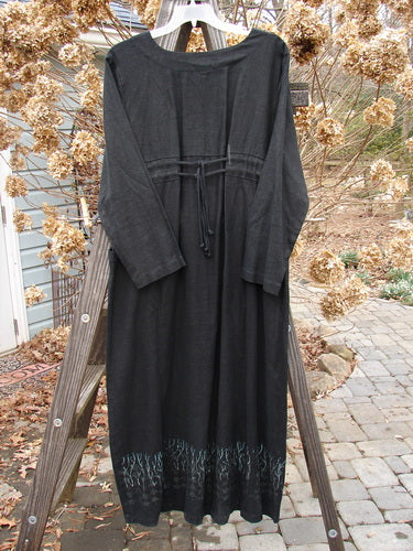 2000 Ringlet Dress Grass Row Black Size 1 displayed on a wooden ladder. The dress features oversized pockets, a rounded V neckline, and sectional panels in thick linen.
