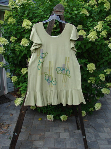1996 Butterfly Dress Pebble Path Seedling Size 2 displayed on a wooden swing. Features ruffled sleeves, lower hem flounce, rounded neckline, and slight A-line flair.