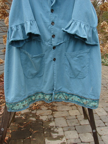 A Barclay Decora Brushed Twill Flutter Coat in Peacock, size 2. A blue jacket with ruffles on a rack.