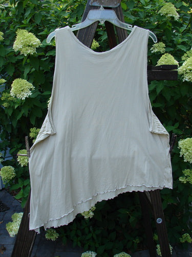Barclay Batiste Curly Seam Tank Rain Sand Size 2 displayed on a wooden rack, showcasing curly edgings, asymmetrical hem, and deeper arm openings.